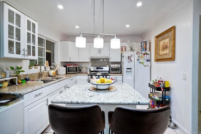 kitchen with decorative light fixtures, sink, stainless steel appliances, and white cabinets