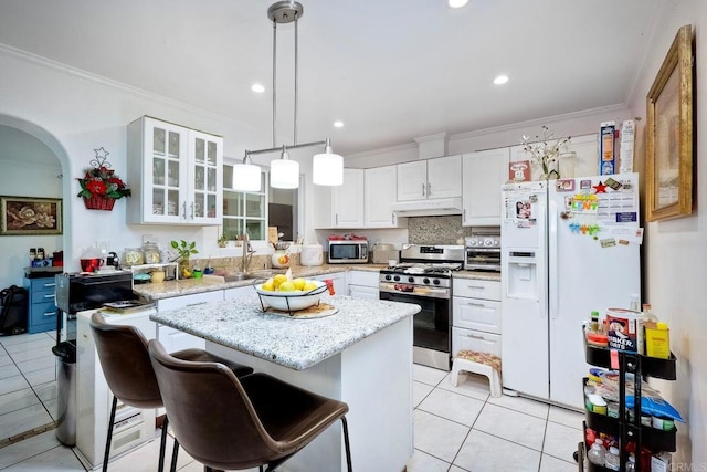 kitchen with white cabinets, pendant lighting, stainless steel appliances, crown molding, and a center island