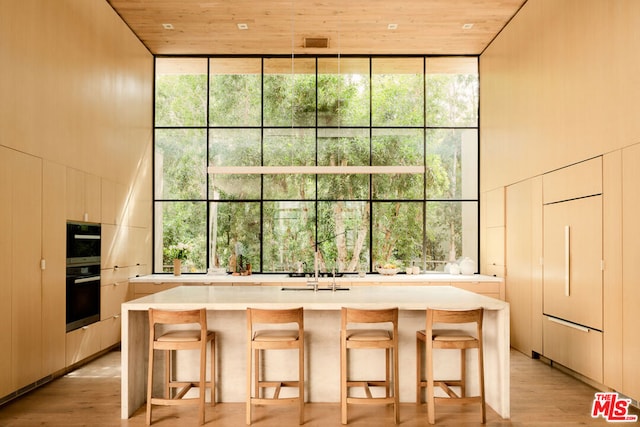 kitchen with paneled built in fridge, wood ceiling, a kitchen breakfast bar, and a healthy amount of sunlight