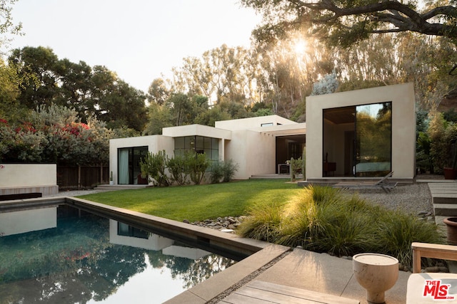 rear view of property featuring a lawn and a patio