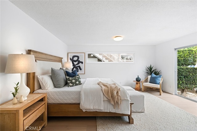 bedroom with wood-type flooring, a textured ceiling, and access to outside