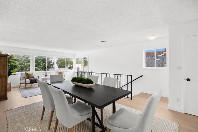 dining space featuring a textured ceiling and light wood-type flooring