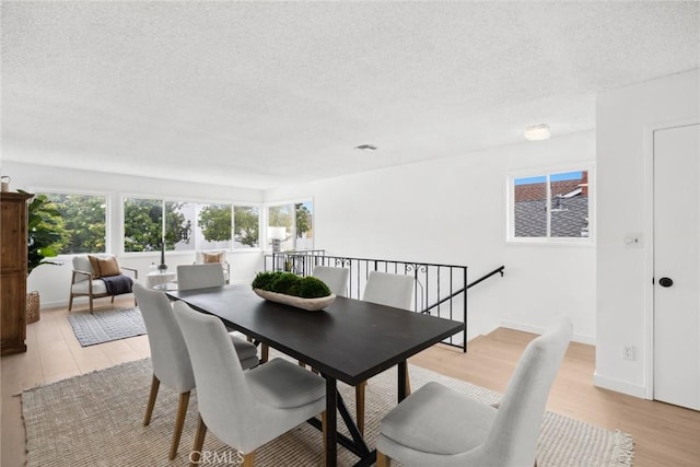 dining area with light wood-style flooring and a textured ceiling
