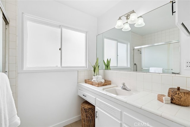 bathroom with backsplash, vanity, and a shower with shower door