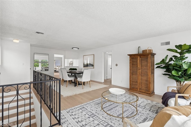 living room with a textured ceiling and light hardwood / wood-style flooring