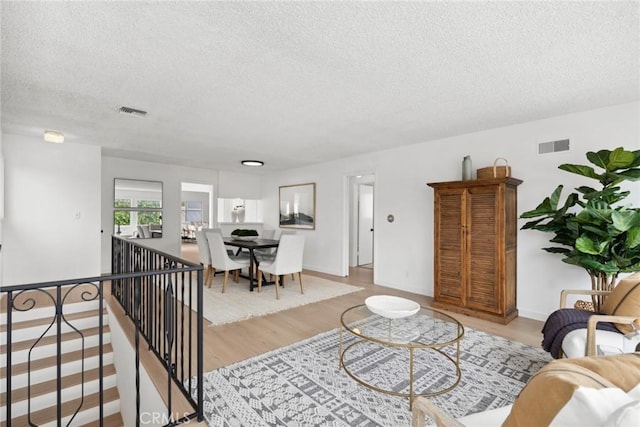 living room with wood finished floors, a textured ceiling, and visible vents