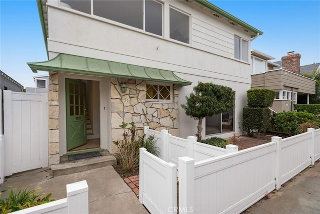 property entrance with stucco siding, fence, and stone siding