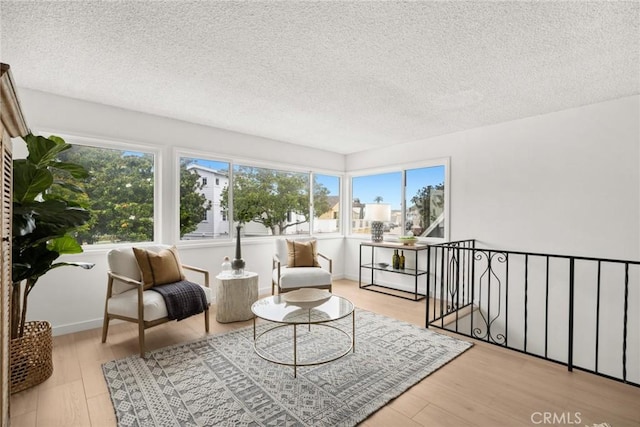 sitting room with a wealth of natural light, wood finished floors, and a textured ceiling