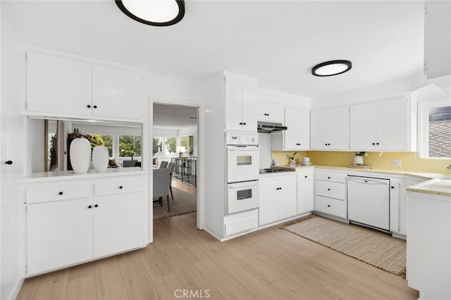 kitchen featuring white cabinets, light wood-type flooring, white appliances, light countertops, and under cabinet range hood