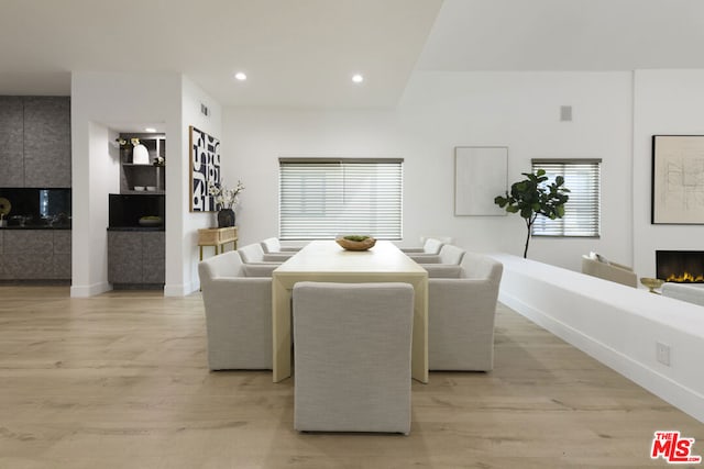 dining area featuring a large fireplace, plenty of natural light, and light wood-type flooring