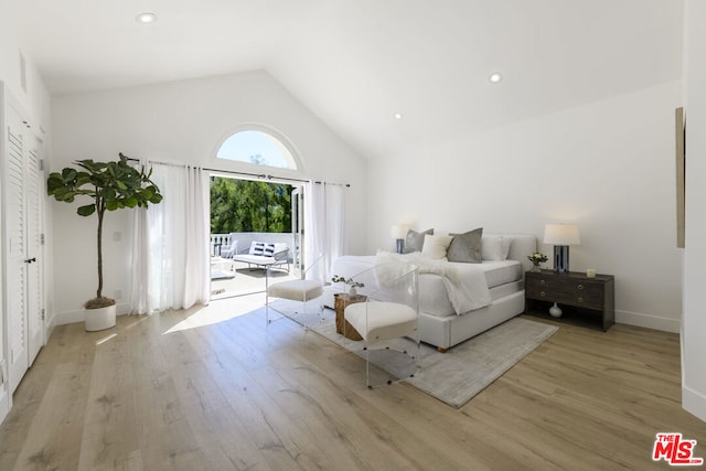 bedroom featuring access to exterior, high vaulted ceiling, and light hardwood / wood-style floors