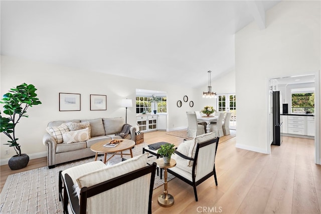 living room featuring beamed ceiling, a chandelier, light hardwood / wood-style floors, and high vaulted ceiling