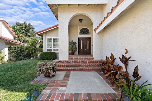 entrance to property featuring french doors and a lawn