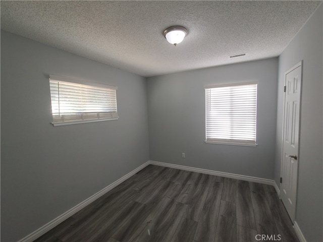 spare room featuring a textured ceiling and dark wood-type flooring