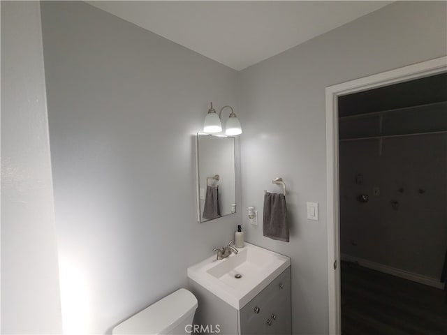 bathroom with hardwood / wood-style flooring, vanity, and toilet