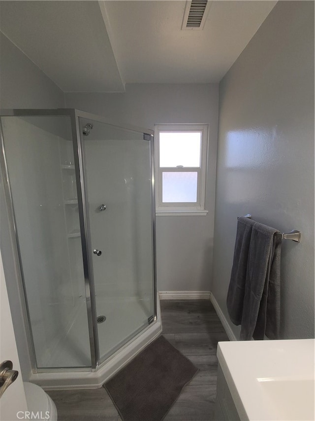 bathroom featuring a shower with door, hardwood / wood-style floors, and toilet