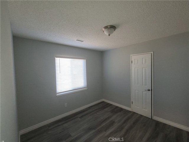 unfurnished room with a textured ceiling and dark hardwood / wood-style floors