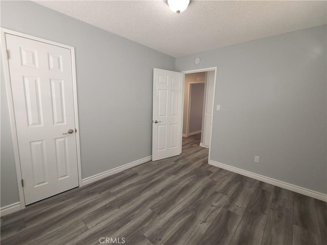 38633 Glenbush Ave, Palmdale, CA 93550 - empty room with dark wood-type flooring, baseboards, and a textured ceiling