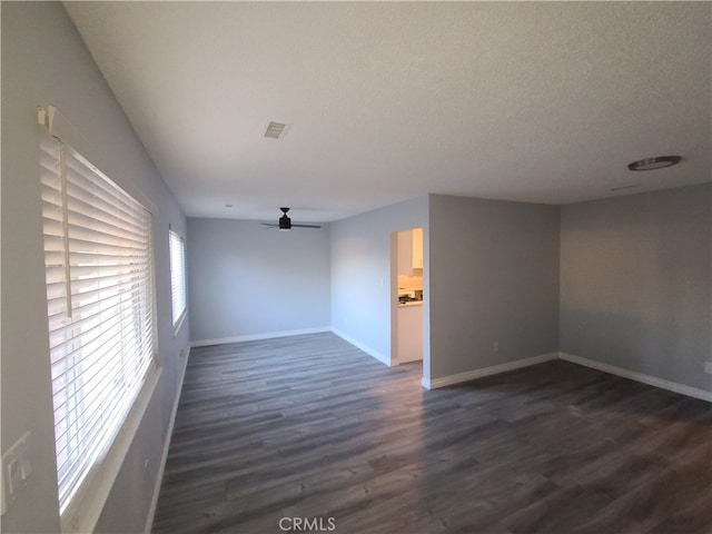 empty room featuring ceiling fan, a textured ceiling, and dark wood-type flooring