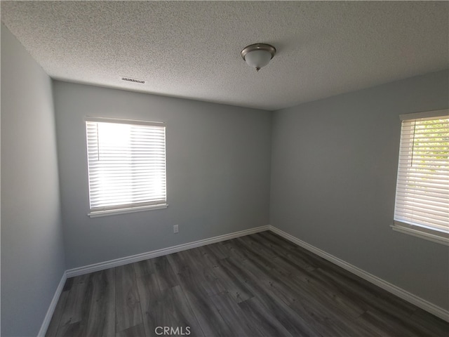 empty room with a textured ceiling and dark hardwood / wood-style flooring