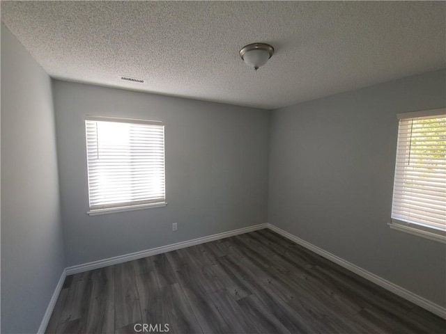 38633 Glenbush Ave, Palmdale, CA 93550 - spare room with dark wood-style floors, a textured ceiling, healthy amount of natural light, and baseboards