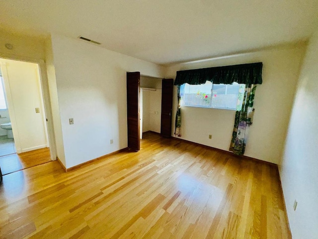 unfurnished bedroom featuring connected bathroom and wood-type flooring