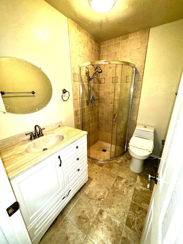 bathroom with a shower with door, vanity, and toilet