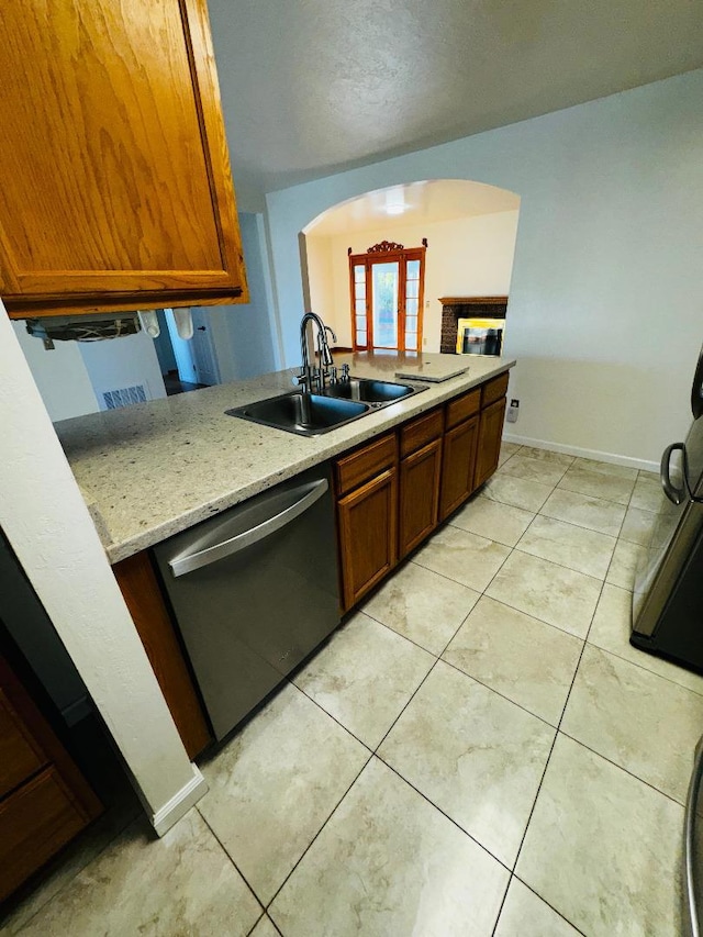 kitchen featuring sink, light tile patterned floors, dishwasher, light stone countertops, and kitchen peninsula