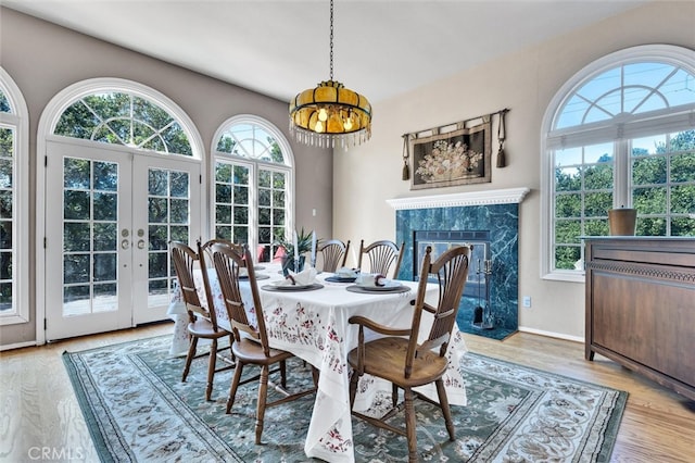 dining room with french doors, a notable chandelier, light wood-type flooring, and a fireplace