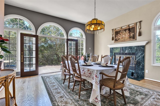 dining area with a premium fireplace, a healthy amount of sunlight, hardwood / wood-style floors, and a chandelier