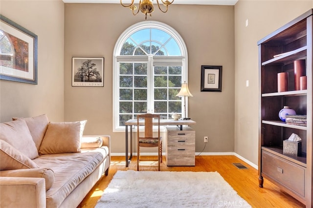 office area with light wood-type flooring and an inviting chandelier