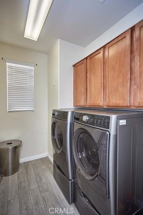 laundry area featuring cabinets, light hardwood / wood-style floors, and washing machine and clothes dryer