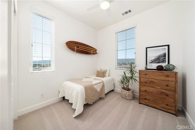 bedroom featuring ceiling fan, light colored carpet, and multiple windows