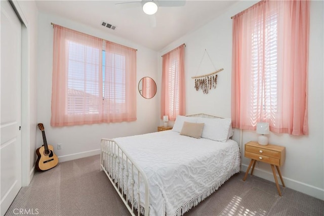 carpeted bedroom with multiple windows, ceiling fan, and a closet