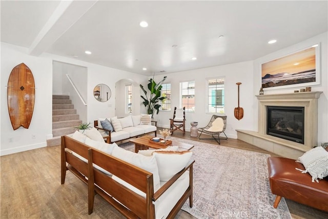 living room featuring beamed ceiling, a fireplace, and light hardwood / wood-style flooring