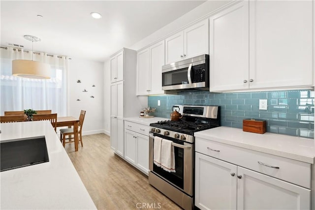 kitchen featuring tasteful backsplash, light wood-type flooring, white cabinets, and appliances with stainless steel finishes