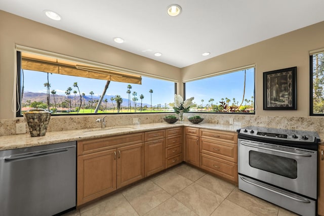 kitchen with a mountain view, light stone countertops, sink, and stainless steel appliances