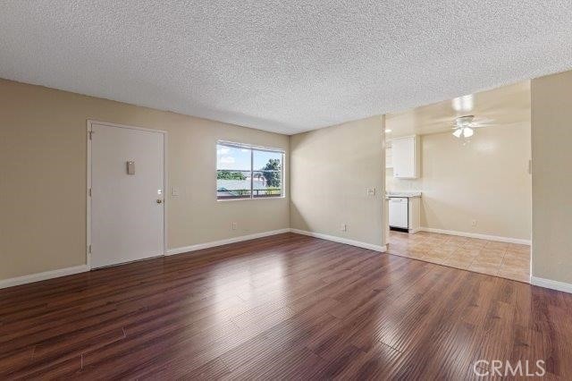 unfurnished living room with wood-type flooring, a textured ceiling, and ceiling fan