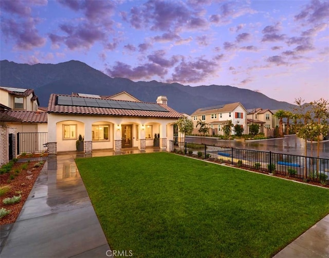 back house at dusk with a lawn, solar panels, and a mountain view