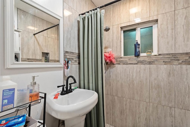 bathroom with a shower with curtain, tile walls, and sink