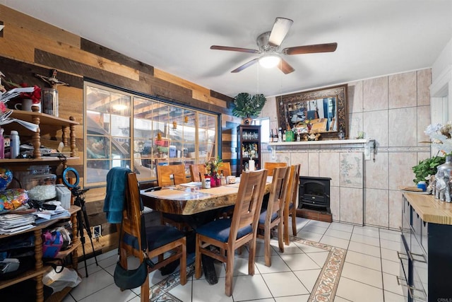 tiled dining area with a wood stove, tile walls, and ceiling fan