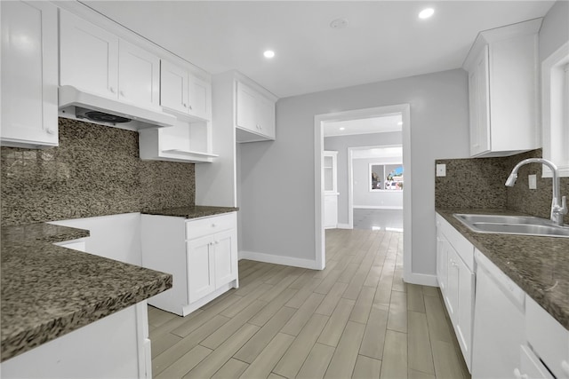 kitchen featuring white cabinets, dishwasher, dark stone countertops, and sink