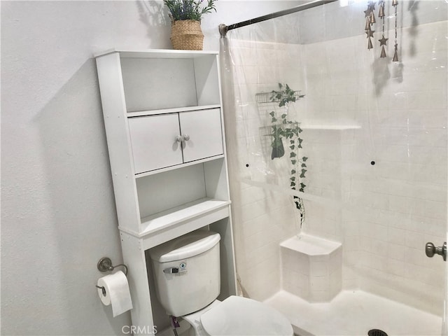 bathroom featuring tiled shower and toilet