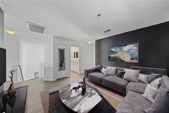 living room with a textured ceiling and light hardwood / wood-style flooring