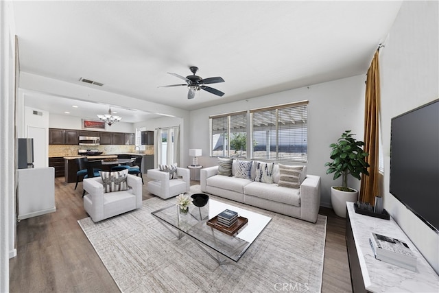 living room with wood-type flooring and ceiling fan with notable chandelier