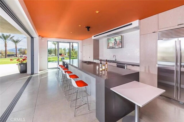 kitchen featuring built in fridge, decorative backsplash, a kitchen island, and a kitchen bar