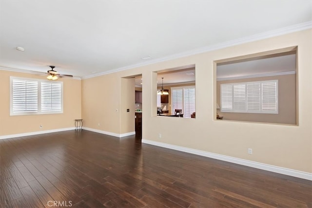 empty room featuring ornamental molding, ceiling fan with notable chandelier, plenty of natural light, and dark hardwood / wood-style flooring