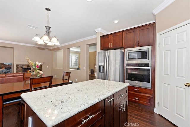 kitchen with pendant lighting, dark wood-type flooring, stainless steel appliances, a center island, and a fireplace