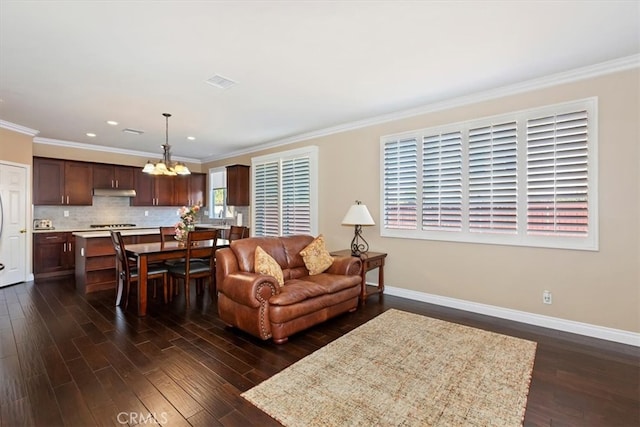 living room featuring an inviting chandelier, crown molding, and dark hardwood / wood-style floors