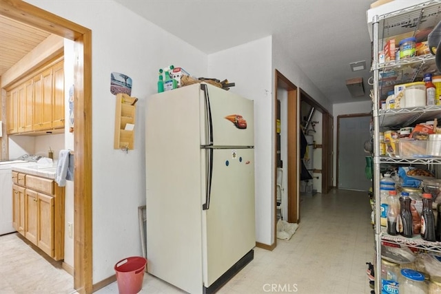 kitchen featuring white refrigerator, light brown cabinets, and washer / dryer